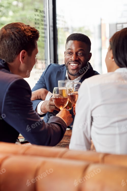 Preview: Group Of Business Colleagues Making A Toast As They Meet For Drinks And Socialize In Bar After Work