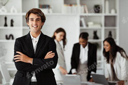Preview: Happy european businessman in suit standing with folded arms in front of his colleagues, posing in