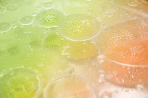 Preview: abstract lime green and orange background formed by drops of oil on water