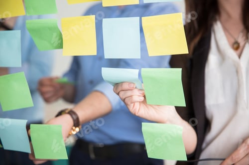 Preview: Midsection Of Business People Sticking Adhesive Notes On Glass
