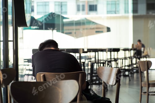 Preview: Back portrait of man sits and works at the coffee shop with blurred people working in background.