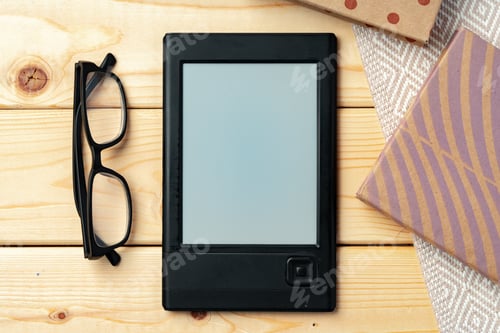 Preview: Portable e-book reader on wooden background top view