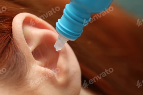 Preview: Woman applying medical ear drops, macro view
