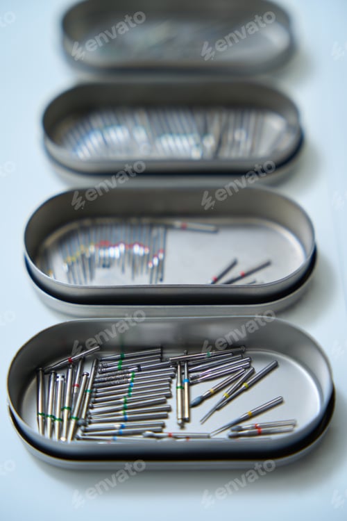 Preview: Close-up of four containers with dental cutters on white table