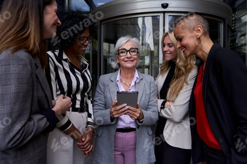 Preview: Mature businesswoman looking at camera cheerfully using a tablet to show the new ideas.