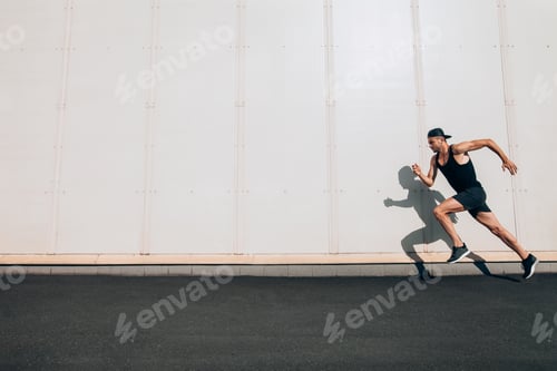 Preview: Young man runner running along wall with copy space