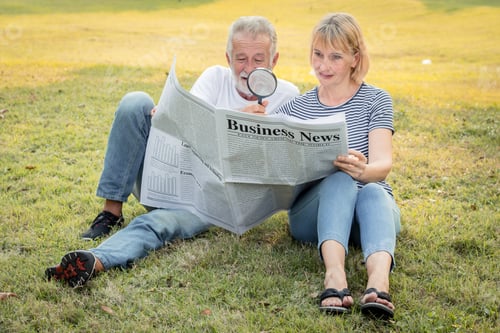 Preview: Senior couple is sitting watching newspapers on the lawn.
