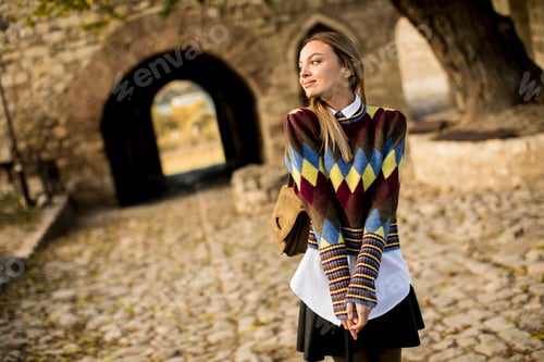 Preview: Young woman standing outside at sunny autumn day