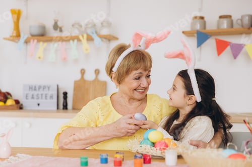Preview: Happy easter! A grandmother and her granddaughter painting Easter eggs