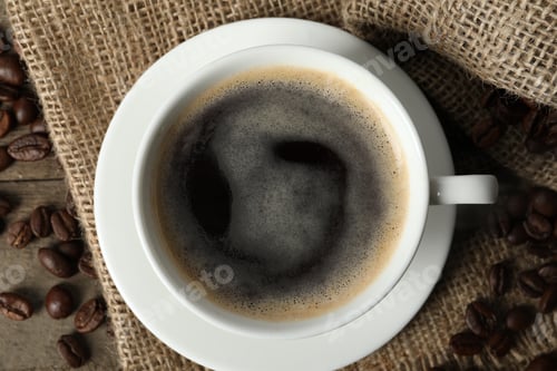 Preview: Cup of aromatic coffee and beans on wooden table, top view