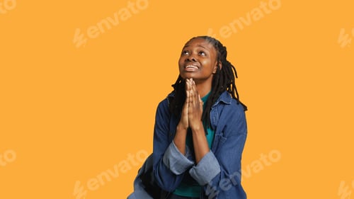 Preview: Religious girl doing worship gesturing, waiting for miracle, studio background