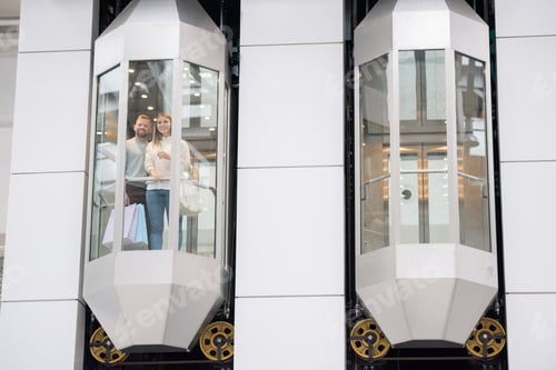 Preview: Young dates standing in one of elevators and looking through window