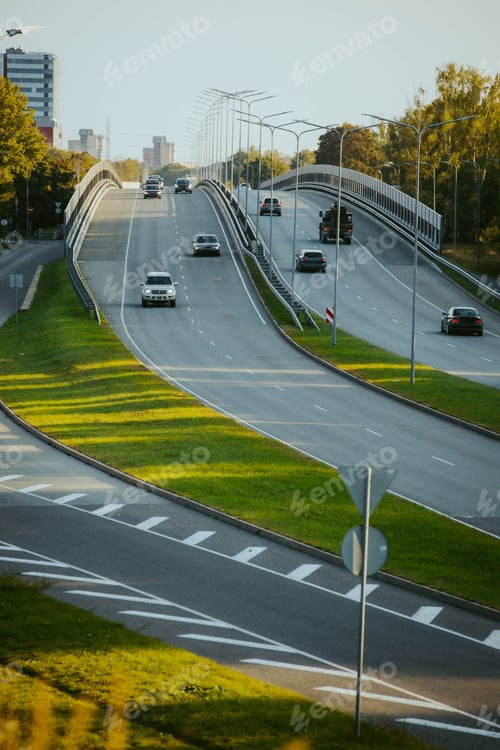 Preview: Vertical top view of cars driving along a highway road in the evening time under a sunny blue sky
