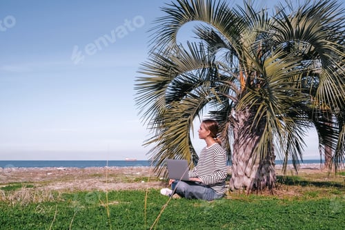 Preview: Remote work.Girl freelancer works remotely sea shore. workation, remote work,leisure, work life bala