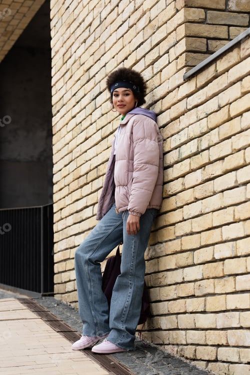 Preview: African american woman looking at camera near building on street