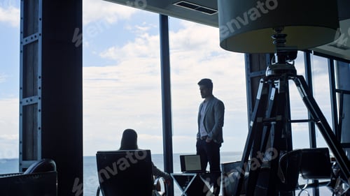 Preview: Business couple silhouettes thinking at marine view. Coworkers discussing deal