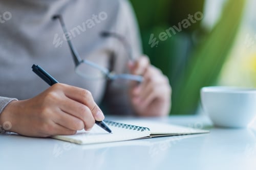 Preview: Closeup image of a woman writing on a blank notebook on the table