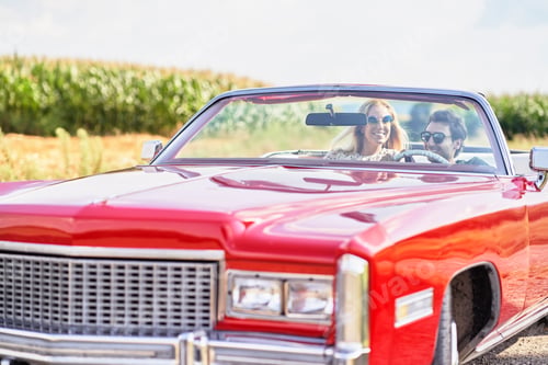 Preview: Smiling couple in a red old car