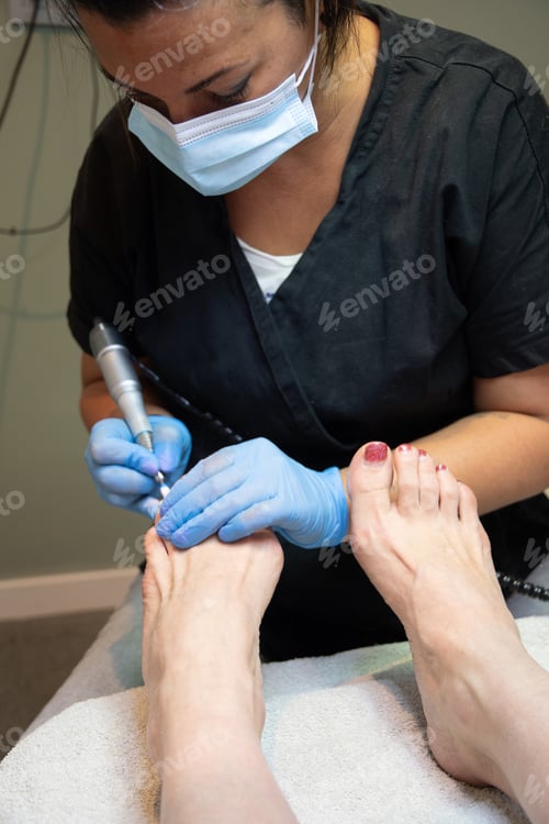 Preview: A master in a beauty salon makes a hardware pedicure to a client, soft focus