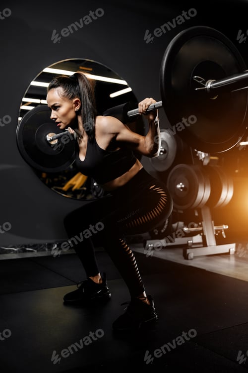 Preview: Photo of powerful woman doing squats exercises with heavy barbell in the gym