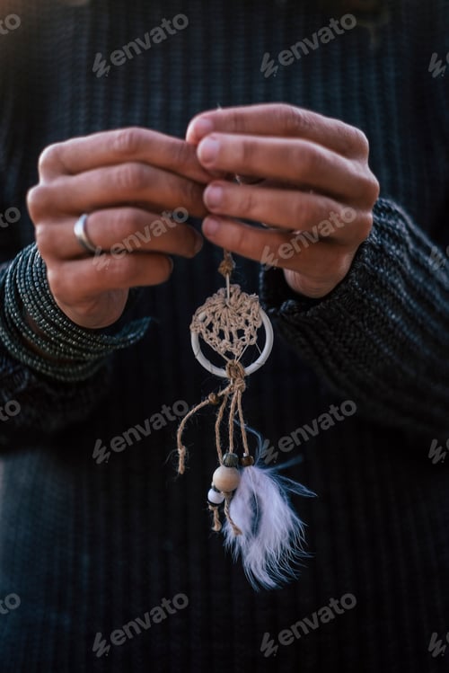 Preview: closeup of woman caucasian hands taking a hand made chic dreamcatcher
