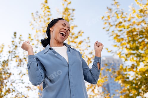 Preview: Excited woman celebrating success outdoors during autumn