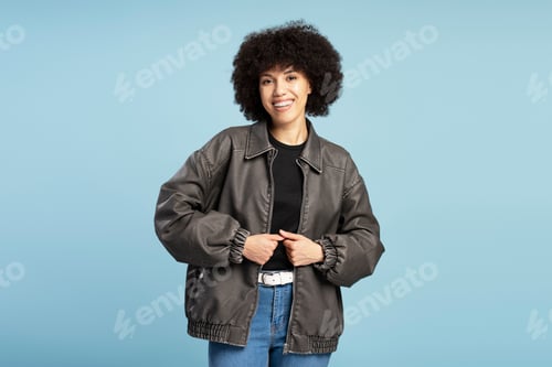 Preview: Smiling Latin woman smiling and wearing a leather jacket on blue background