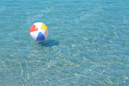 Preview: Colorful beach ball floating in sea on sunny day, space for text