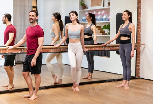 Preview: Group of athletic people standing near barre during training