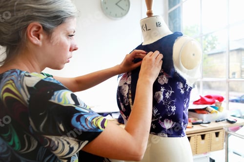 Preview: Fashion designer meticulously pins fabric on mannequin.