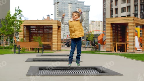 Preview: Slow motion of little boy jumping and having fun on trampoline in new park at city block
