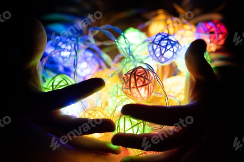 Preview: kid holding a garland in hands, glowing with colorful multicolored lights at night. celebration