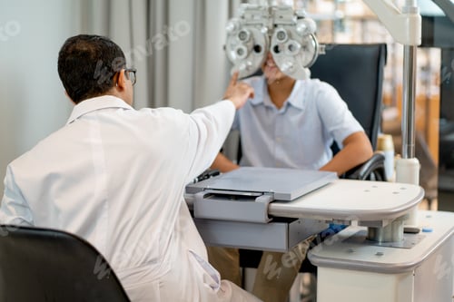 Preview: Back of optical staff use machine to measure eyesight of boy in optical shop.