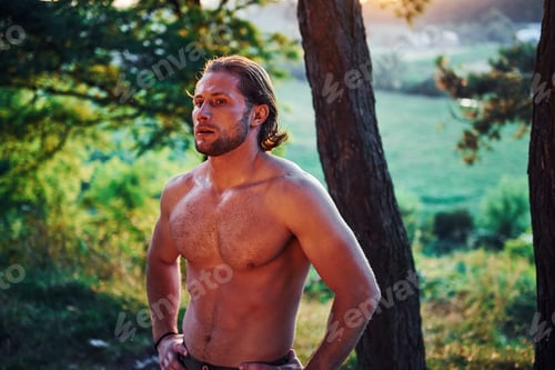 Preview: Beautiful nature. Handsome shirtless man with muscular body type is in the forest at daytime