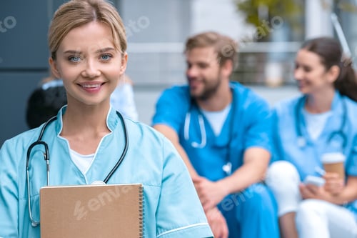 Preview: smiling medical student standing with notebook and looking at camera