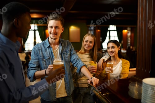 Preview: Friends with beer make a toast at counter in bar