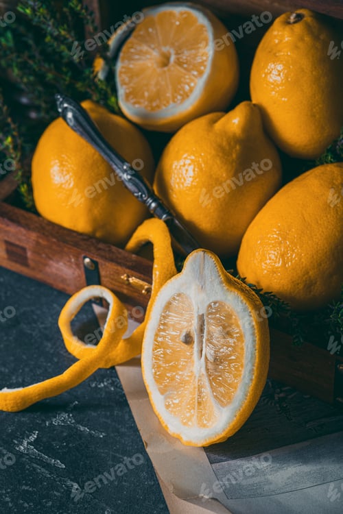 Preview: fresh yellow lemons in a vintage-style box on a dark stone background prepared for tea