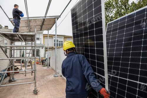 Preview: Workers installing solar panels on building roof using scaffolding