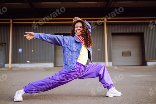 Preview: Funky young woman with american bandana dancing alone in the street.Sport, dancing and urban culture