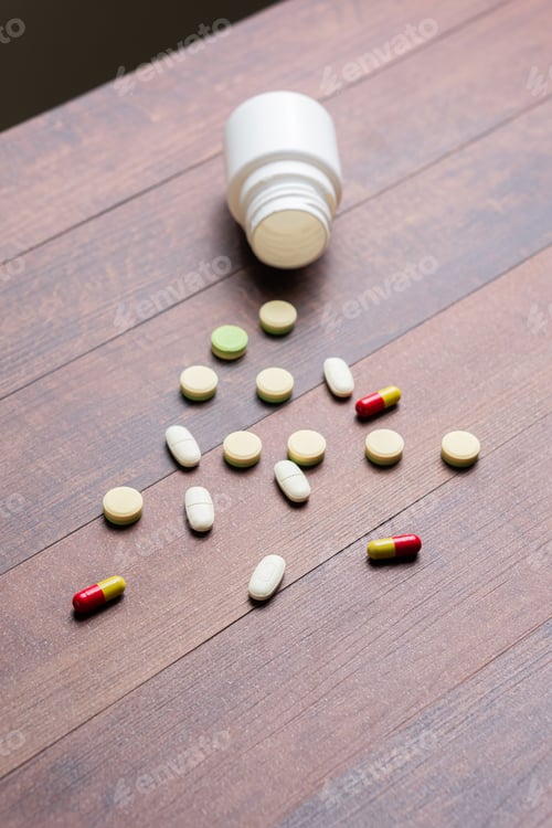 Preview: Scattered Pills and Syringe on Wooden Table
