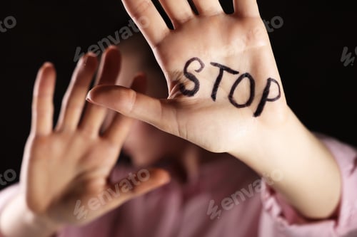 Preview: Woman with word Stop written on hand against dark background, closeup. Domestic violence concept
