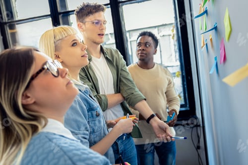 Preview: Diverse group of young business people working in office using colorful sticky notes.