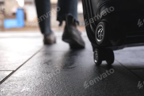 Preview: Closeup image of a woman's feet while traveling and dragging a black baggage in the outdoors