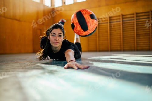 Preview: A young sportswoman is diving for a ball on court on volleyball training.