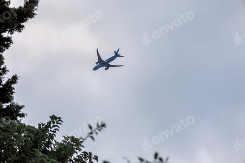 Preview: View of airplane flying in gray sky among white clouds.