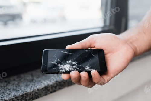 Preview: Cropped view of businessman holding smashed smartphone on blurred background