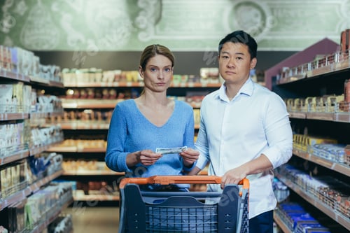 Preview: Upset young couple in supermarket, man and woman looking at camera poor have no opportunity and