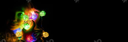 Preview: portrait of a girl holding a garland near face, glowing with colorful multicolored lights at night
