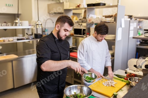 Preview: chef and cook cooking food at restaurant kitchen
