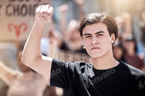 Preview: Fight now while you have the chance. Shot of a young man with his fist raised at a protest rally.